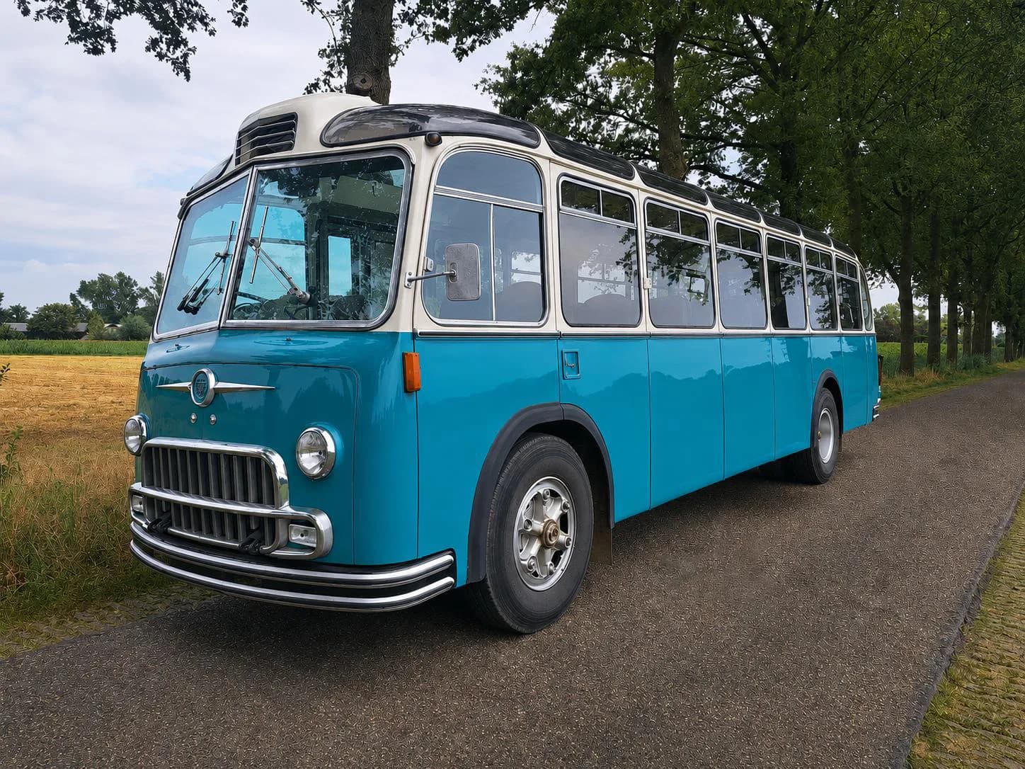 The Montessori Traveling Classroom's turquoise vintage school bus on a tree-lined country road