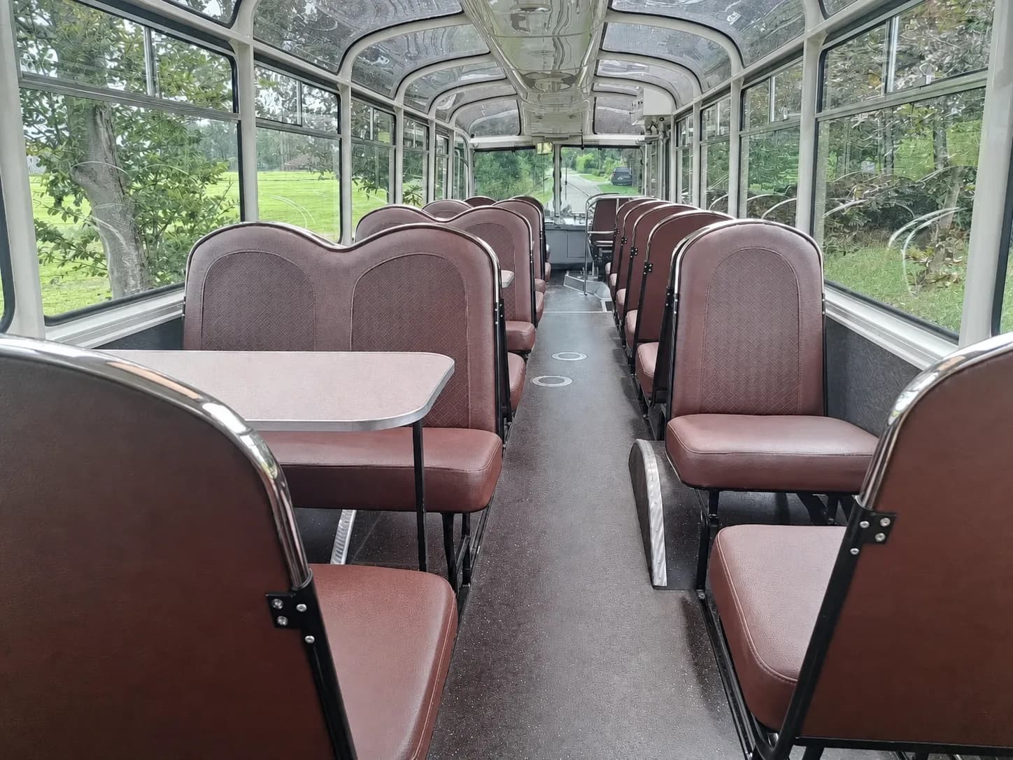 Inside the bus — a glass-roofed mobile classroom with tables between the seats