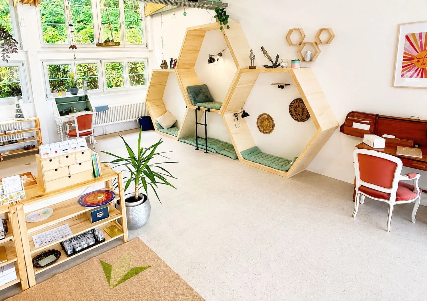 A light-filled Montessori classroom at the Trinity Campus with hexagonal wooden reading nooks and shelves of materials