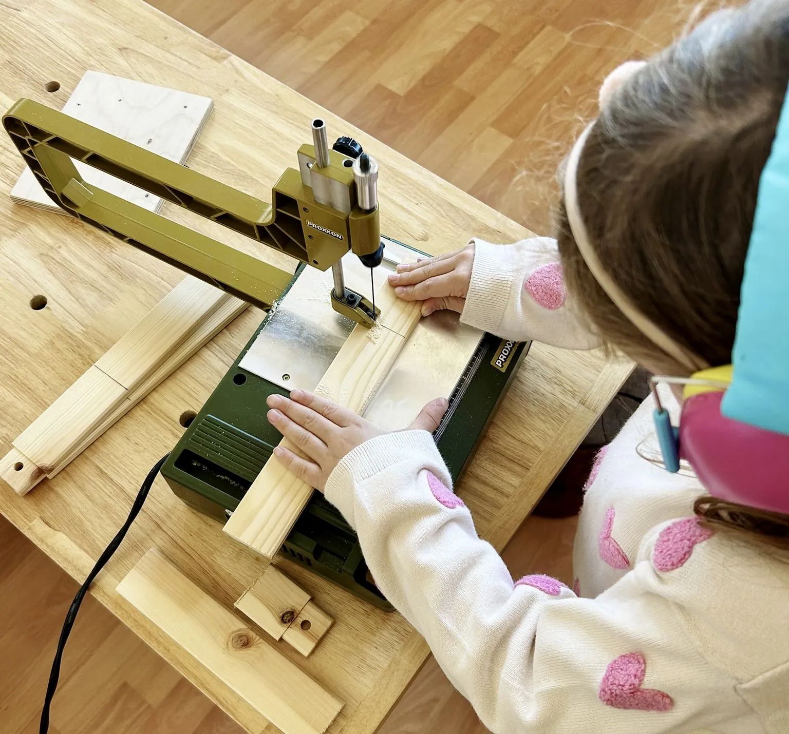 A child using a scroll saw in the Trinity woodworking room
